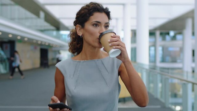hispanic business woman in airport walking using smartphone texting in corporate office typing text messages on mobile phone drinking coffee successful female executive at work 4k footage