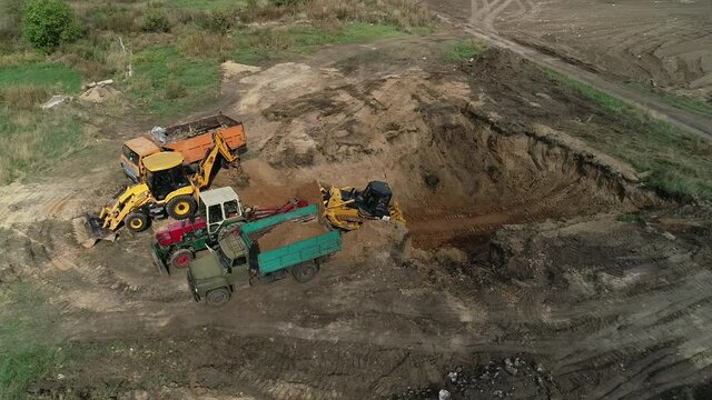 Drone view of a massive pit and heavy machinery removing dirt out of it