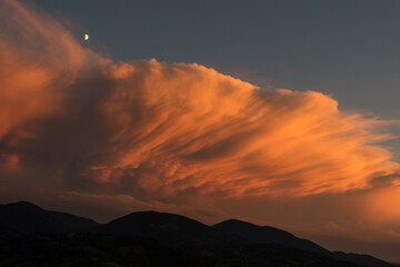 Mammatus clouds over the mountains at sunset with crescent moon. Valle Seriana (Seriana Valley), Italy. 
