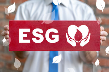 Concept of ESG Environmental Social Governance. Businessman holdes a wooden sign board with ESG...