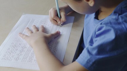 Cute child diligently writes in notebook. Homeschooling on quarantine.