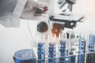 closeup-pipette dropping a sample into a test tube in an experiment research in laboratory