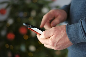 online shopping.Christmas and New Year shopping.Buying holiday gifts.Credit card and mobile phone in hands on shining Christmas tree background.Internet shopping. 