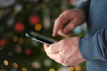Christmas and New Year shopping. Festive online shopping.Credit card and mobile phone in hands on shining Christmas tree background.Internet shopping. 
