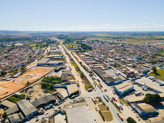 Visão aérea da região central da cidade de Texeira de Freitas, com bairros residenciais,  aera industrial e comercial com a BR101 cruzando a cidade.