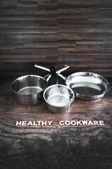 healthy cooking concept, stainless steel pots and pans with Healthy Cookware text in front of them