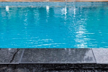 Fototapeta na wymiar Wide swimming pool and brown stone floor inside the villa