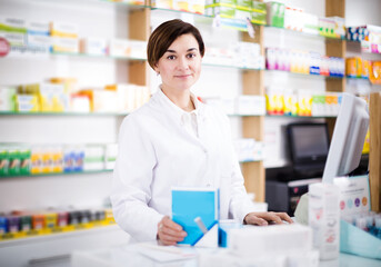 Portrait of smiling woman pharmacist ready to assist in choosing at counter in pharmacy
