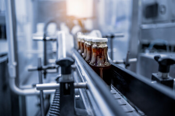 Factory interior of beverage, Production line of manufacturing and packaging juice products, Close up, Glass bottles with screw caps standing on a conveyor belt.