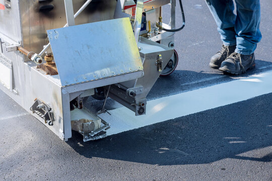 Workers Apply White Paint A Road Marking The Stripes With A Reflective Powder On The Asphalt