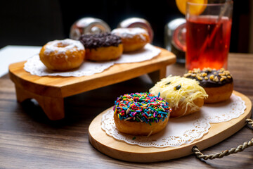 Sugar Doughnuts and chocolate doughnuts on cutting board on wooden cutting board with fruity syrup as background