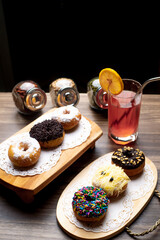 Sugar Doughnuts and chocolate doughnut on cutting board on wooden cutting board with fruity syrup as background
