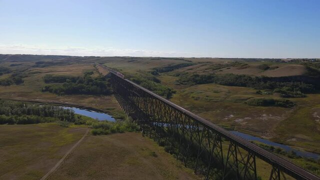 Drone footage of Battle River Trestle Bridge in Wainwright, Alberta. Train oncoming sunny day blue sky