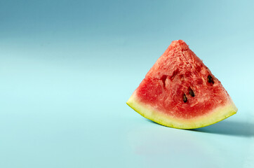 Fototapeta na wymiar A piece of sweet watermelon on a blue background. A ripe watermelon on a colored background is a place for text. 