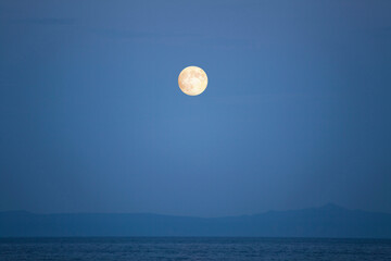 満月が知床の海から見る国後島の上に輝く