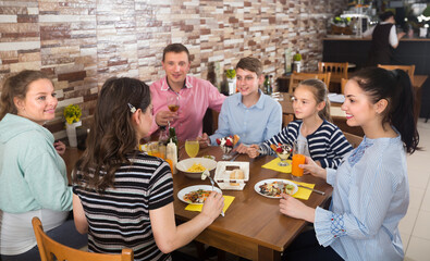 Obraz premium Big friendly family having fun and dinning in cafe