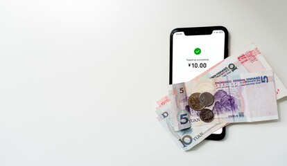 Chinese Yuan Money banknotes and top up smartphone on a white background for using online digital money to pay with QR code scanning, China. Add text