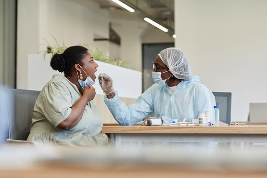 Medical professional doing Covid-19 test to woman with throat swab probe
