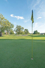 Obraz premium A flag points skyward on a golf course green in late afternoon. 