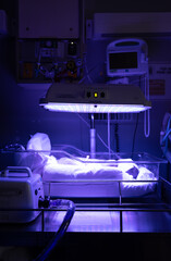 Newborn baby with jaundice lays in Phototherapy bed