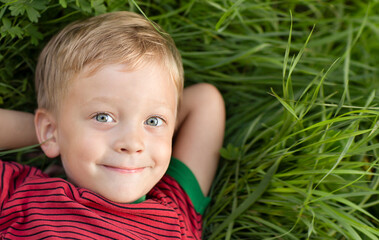 A happy baby lying on the grass and  smiling 