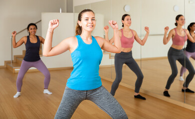 Group of smiling women training sport dance in modern studio