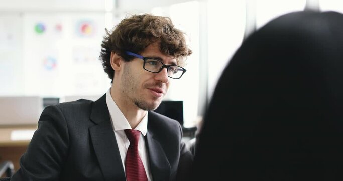 Serious, angry and unhappy face hipster businessman wears eyeglasses sitting with female colleague nearby desktop computer screen and taking with stressed emotion.