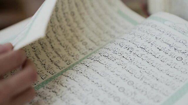 Close up on Arabic book in mosque as pages are turned, slow motion