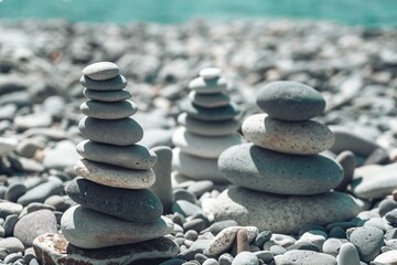 Fototapeta na wymiar Balanced pebble pyramid on the beach on a sunny day. Abstract Sea bokeh on the background. Selective focus. Zen stones on the sea beach, meditation, spa, harmony, calmness, balance concept