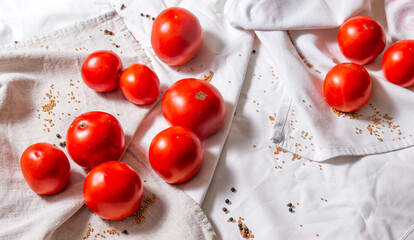 Red ripe tomatoes of light fabric, next to scattered grains of mustard and pepper.