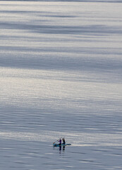 Two women paddle boarding on a calm Puget Sound morning with sunlight playing on the water.