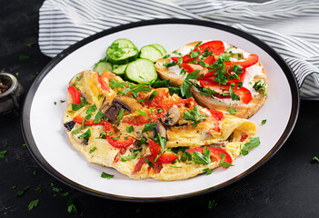 Omelette with mushrooms, paprika, tomatoes and sandwich with cream cheese on white plate. Frittata - italian omelet.