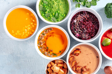 Vegan soup variety with a place for text, organic vegetable cream soups, shot from above on a grey slate background