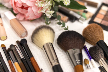 Obraz na płótnie Canvas A set of brushes and professional cosmetics on the makeup artist's desk. Everything for applying makeup. Suitable for your beauty blog. Make up the most necessary things. Flatly. Soft focus.