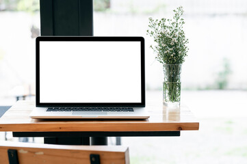 Fototapeta premium Blank screen laptop computer and flower on wooden table with copy space.