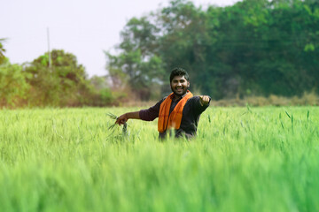 young indian farmer spreading his arms at wheat field