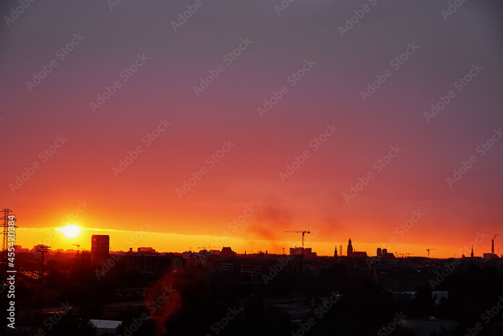 Wall mural sunset over city with buildings silhouette