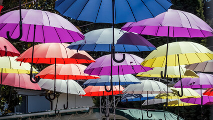 The street is decorated with colorful umbrellas,a cheerful canopy from the sun