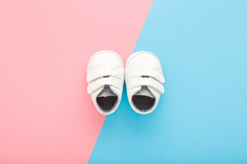White small sport booties for boy or girl on light blue pink table background. Pastel color. Baby footwear. Top down view. Two sides.