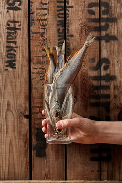Male hand holding glass with air-dried salted sabrefish