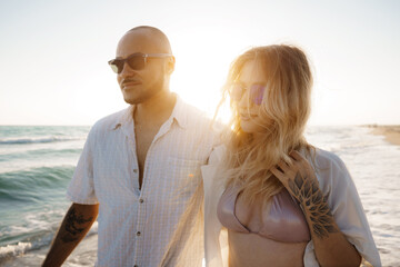 Young beautiful couple walking on beach near sea