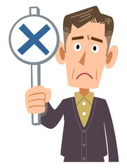 バツ印が描かれた札を見せるカジュアルな服装の年配の男性
