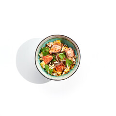 Asian traditional dish - fried rice with egg, vegetables, and salmon. Pan asian wok with rice, egg and fish on white background. Nasi goreng with salmon on isolated background with shadows.