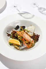 Fresh healthy salad with shrimp, mussels, rucola, lettuce and vegetables. Elegant contemporary appetizers with seafood on white table with wine glass. Still life - Lunch in seafood restaurant.