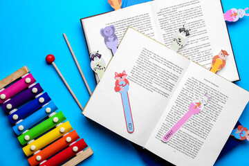 Cute bookmarks with books and xylophone on color background