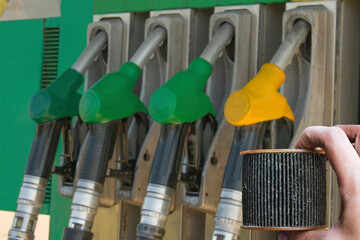 Car mechanic holding in hand old dirty paper fuel filter on gas station background. Clogged Box...