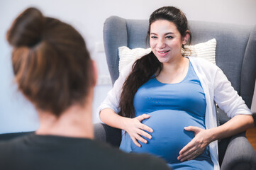 Beautiful young pregnant woman sitting on bed with loving and caring husband trying to connect with...