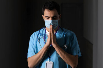 Praying male doctor on dark background