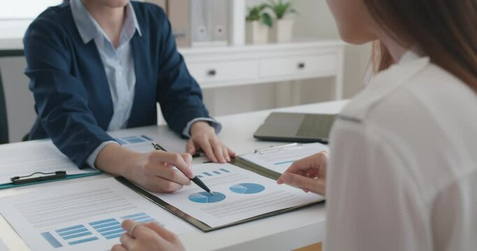 Asia stock trader agent or Sale tax loan broker advice brief and point hand to graph report talk to client at office desk show budget chart data or legal result on claim form. Trust will in work plan.