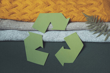 Recycle sign cut out of cardboard on pile of autumn clothes. Recycle clothes concept.
